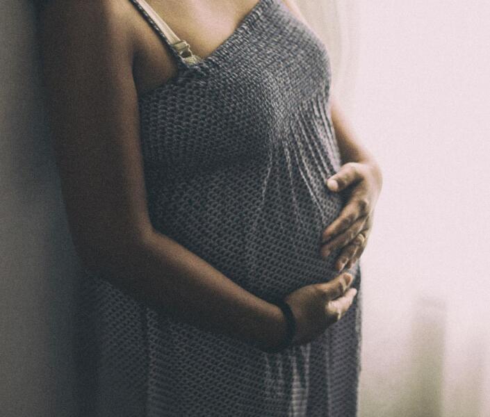 Pregnant woman near window holding tummy