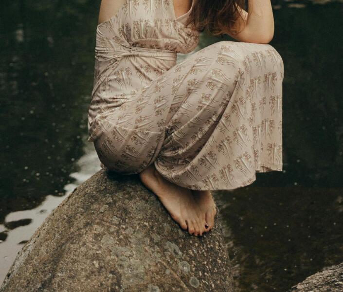 Woman sitting on rock in river